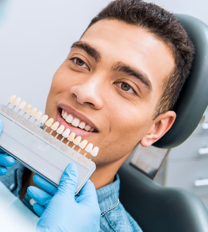 male patient sitting in a dental chair trying to decide what color matches his teeth for dental veneers in las vegas